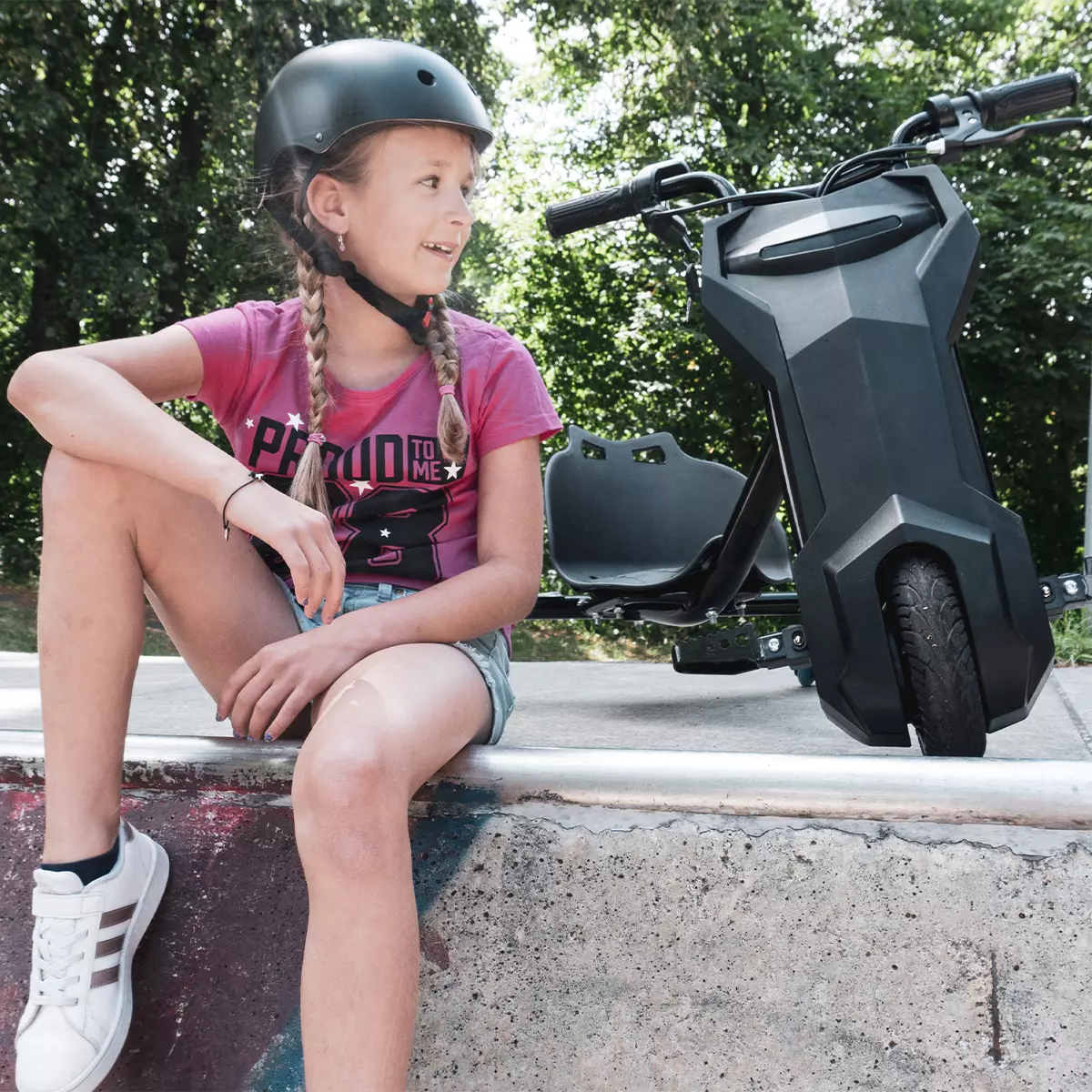 Mädchen sitzt auf Skaterpiste, hinter ihr schwarzes Elektro-Drift-Trike