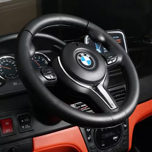 Vergrößertes Lenkrad des Kinder-Elektroautos mit BMW-Emblem in der Mitte 
