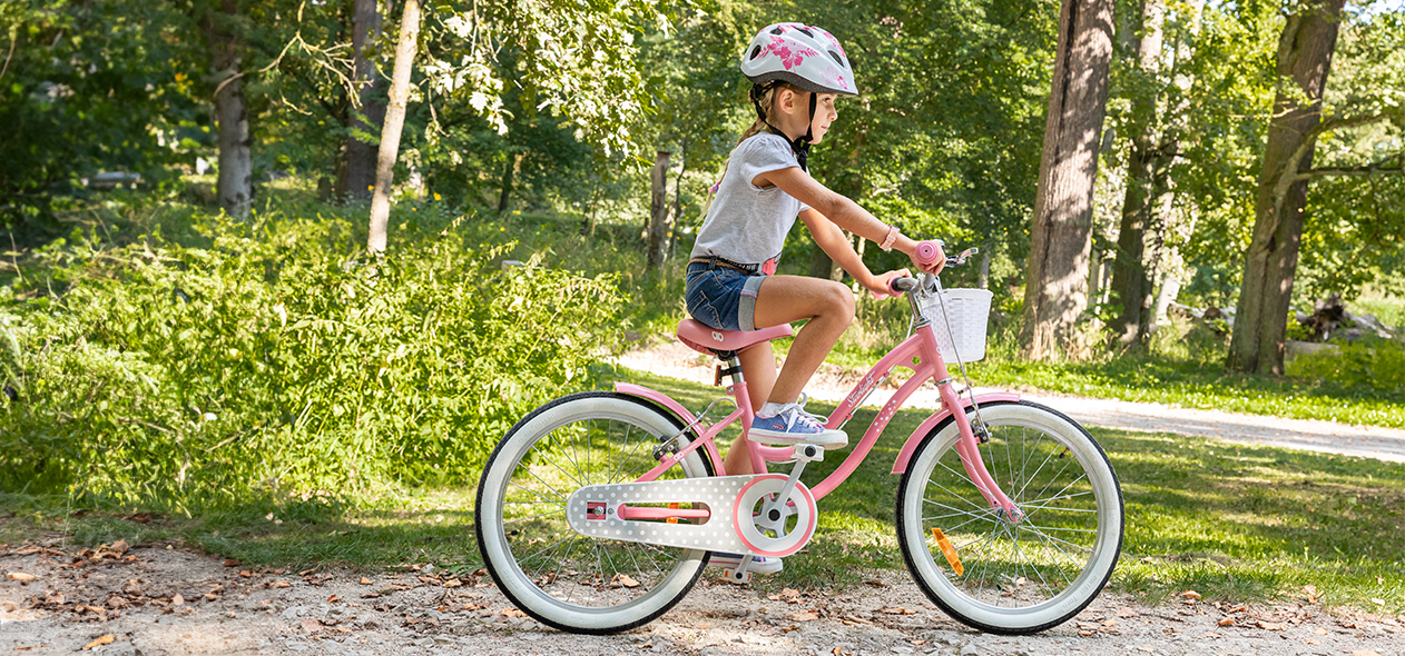 Mädchen mit Fahrradhelm fährt mit dem Kinderrad durch einen Wald