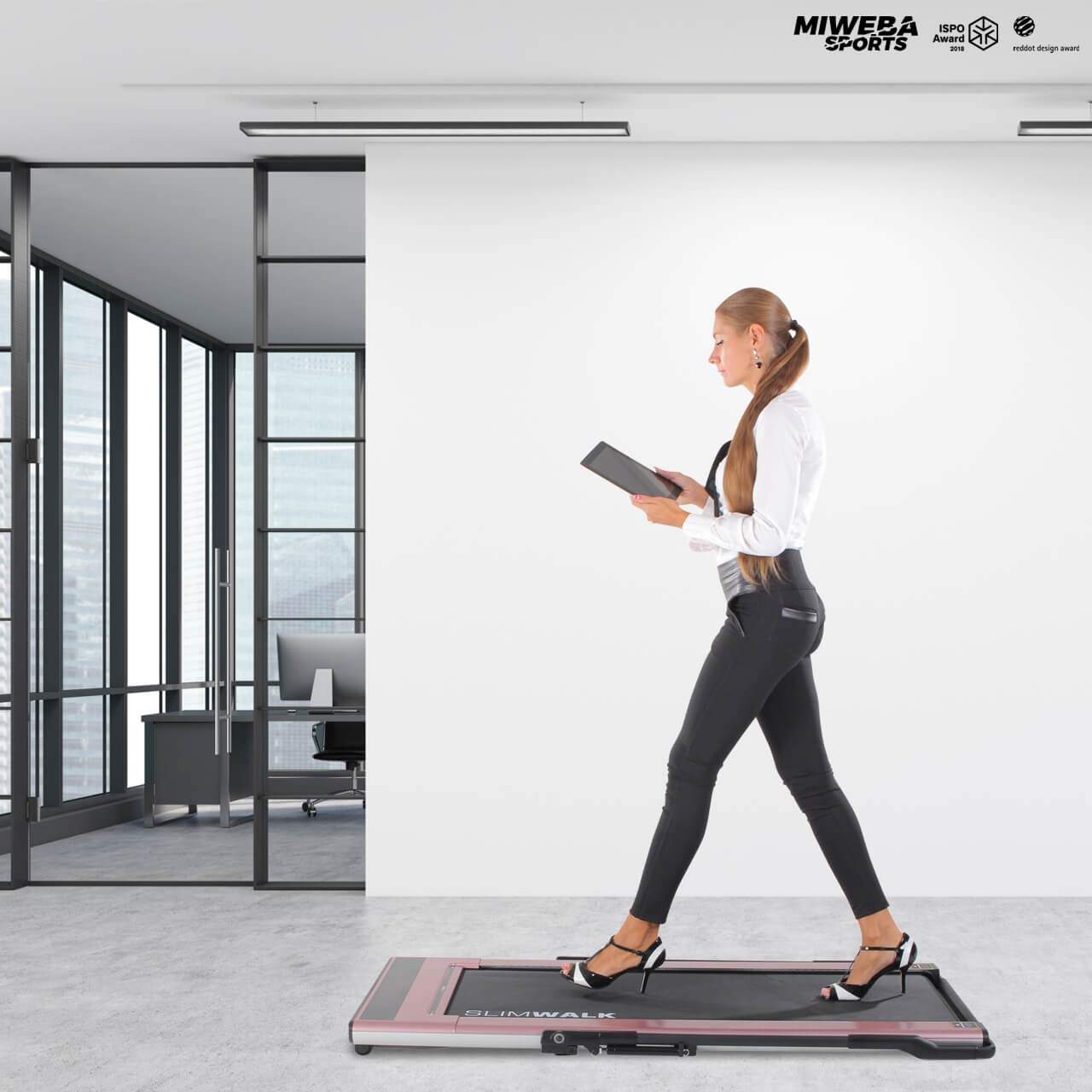 Biegająca kobieta z tabletem na designerskiej bieżni w biurze
